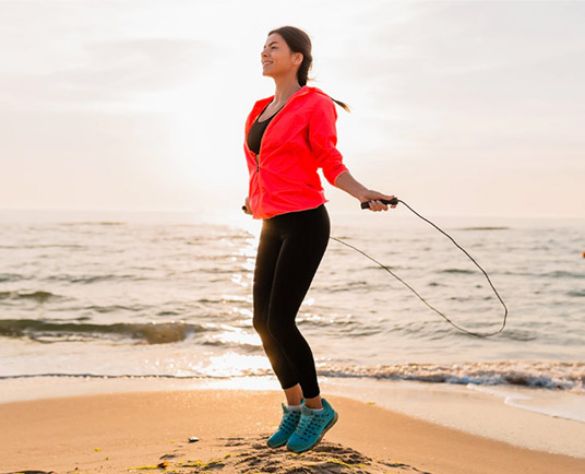 Mulher pulando corda na praia